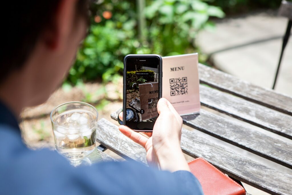 カフェのテーブルでQRコードを読み込んでメニューを調べる男性